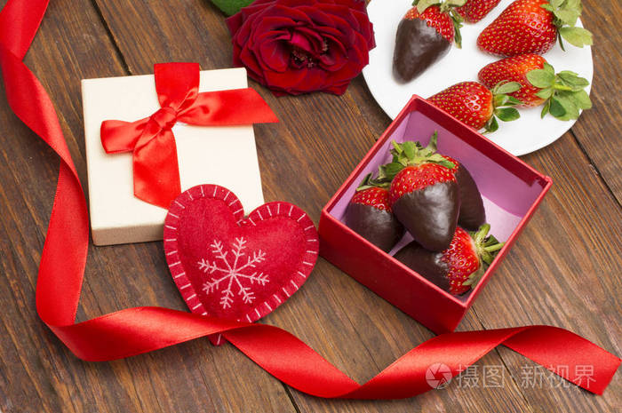 盒子里有美味的巧克力蘸草莓和玫瑰在桌子上。情人节