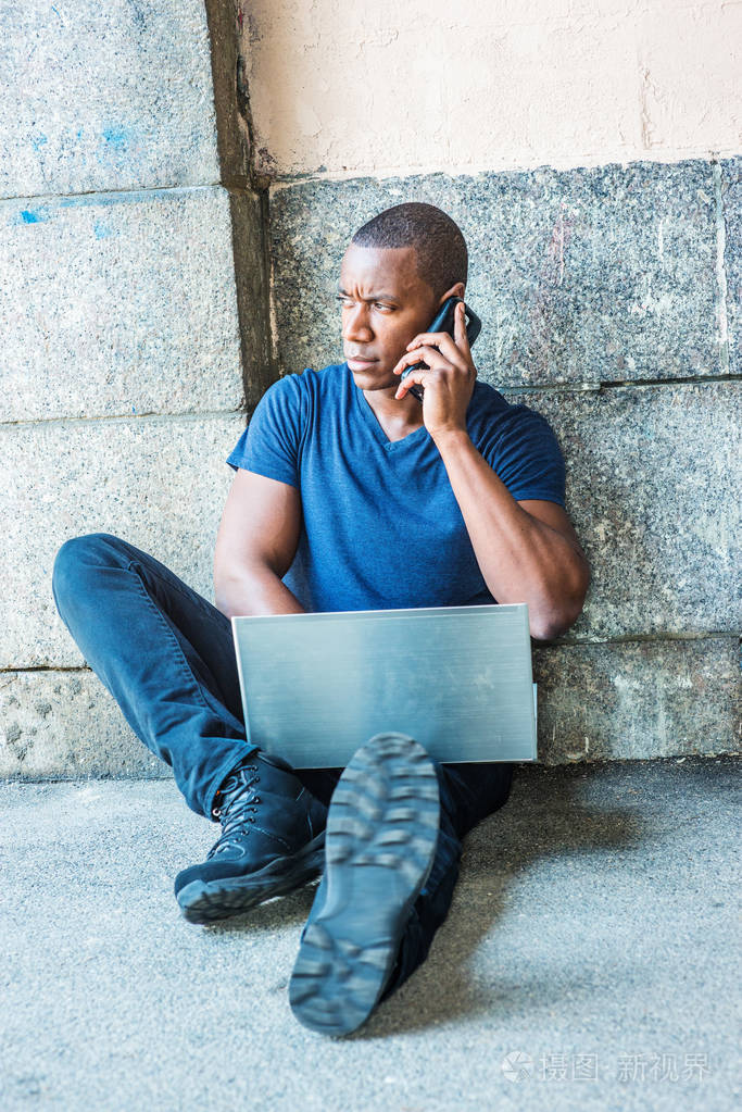 年轻的非洲裔美国人在纽约工作,穿着蓝色的v颈t恤,黑色的裤子,运动鞋