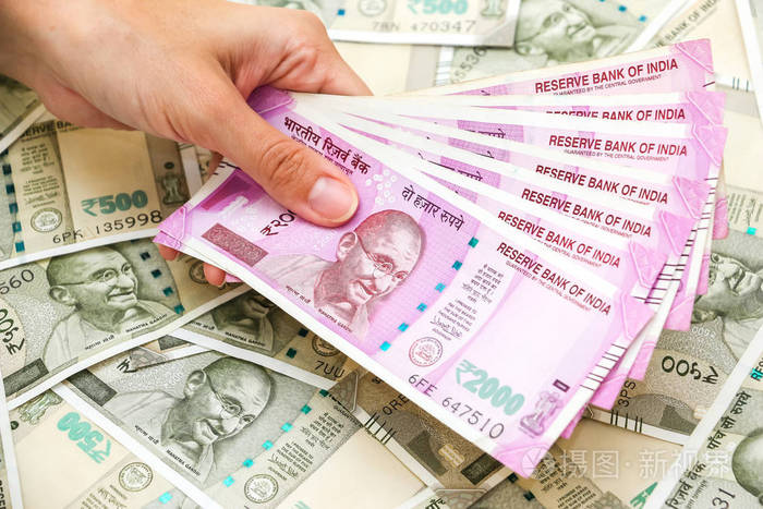 女性手持有全新的2000印度卢比钞票超过500卢比的钞票背景.