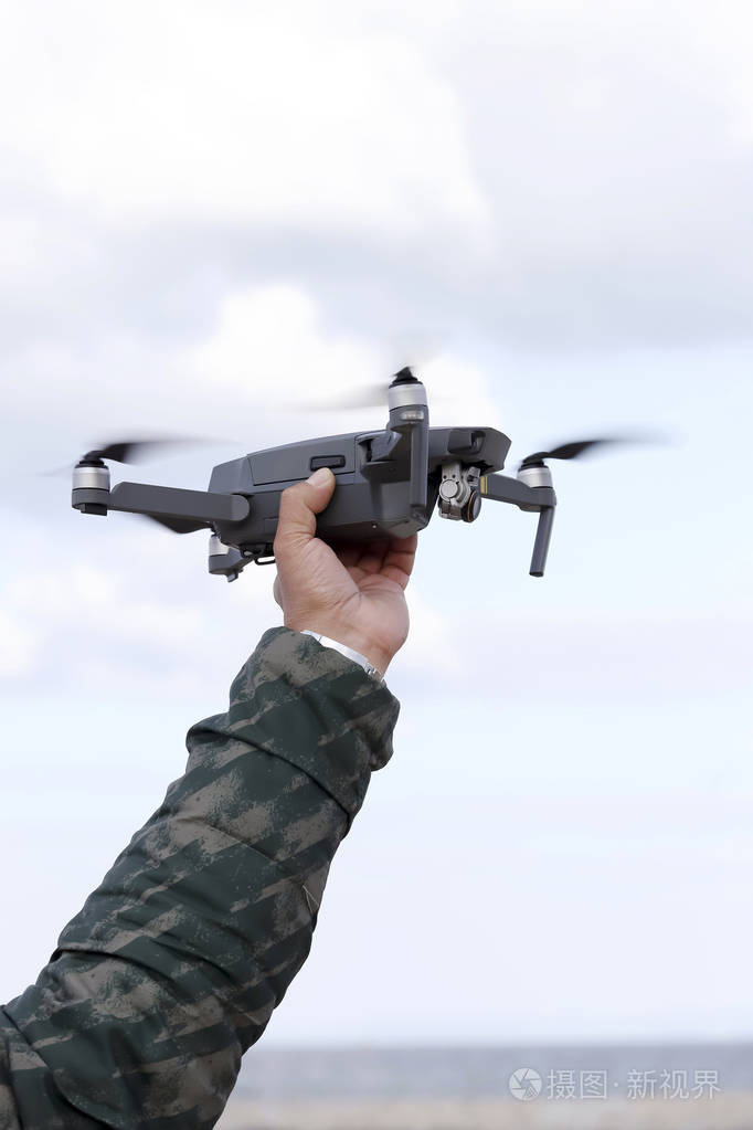 天空背景下的手抓无人驾驶飞机相机操作员的概念