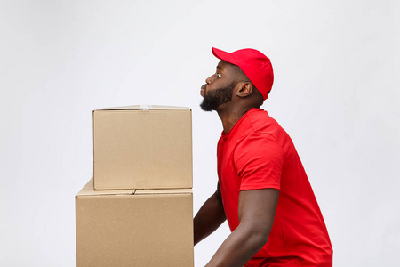 交付非洲人的美国男人在红色衬衫的肖像。他举重量箱子反对有一个被隔绝的在白色背景