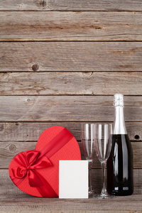 情人节贺卡与心形礼品盒和香槟在木制墙前。 为你的问候留出空间