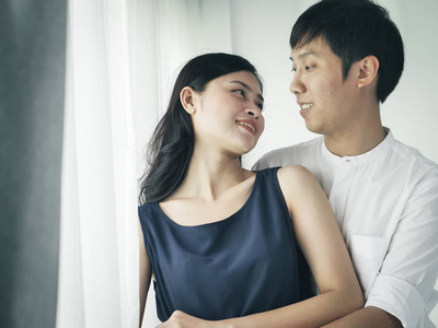 浪漫的亚洲夫妇拥抱和亲吻在家的生活方式概念。