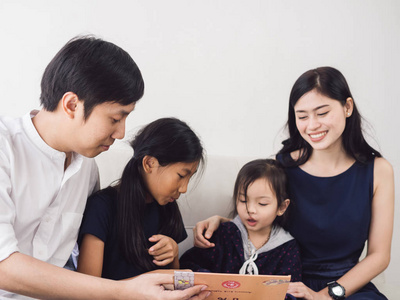 快乐的亚洲家庭一起阅读一本书，在家里的生活方式概念。