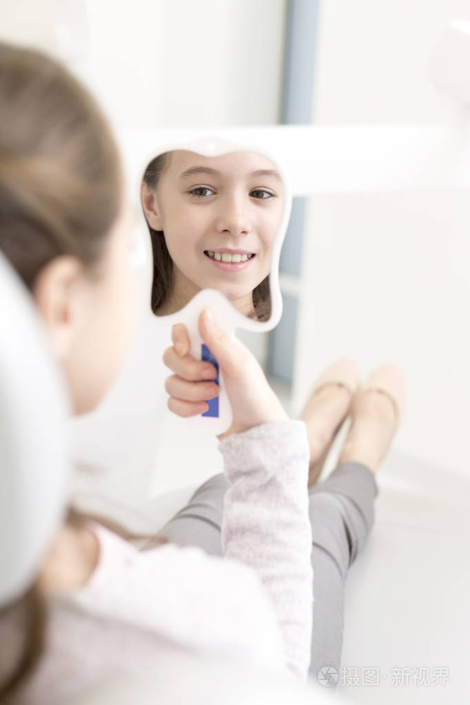 微笑的女病人在牙科诊所照镜子