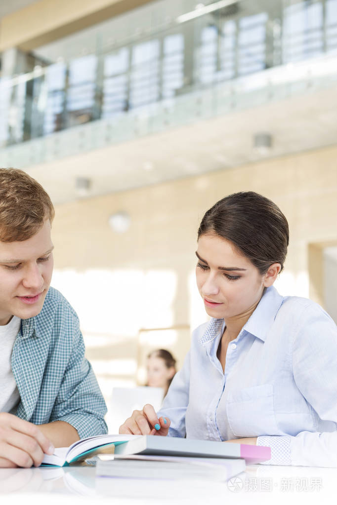 在大学图书馆里朋友们围坐在桌子旁讨论书本问题