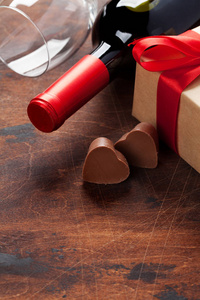 情人节贺卡与酒瓶巧克力心和礼品盒木背景。 为你的问候留出空间
