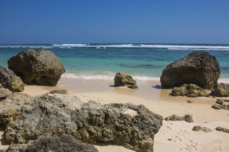 阳光照耀着沙滩上的岩石，有大海和蓝天