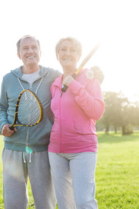 快乐的老夫妇在公园里拿着网球拍