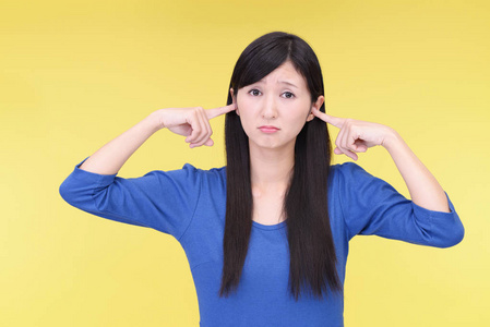 女人在黄色背景下闭上耳朵