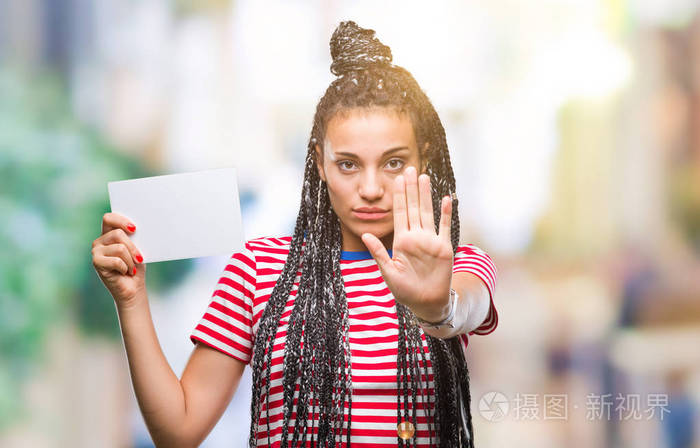 年轻的非裔美国女孩拿着空白卡在孤立的背景上，张开手做停止标志，严肃自信的表情防御手势