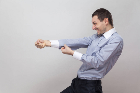 勤奋的商人试图在灰色背景下做拉人手势的侧视图照片