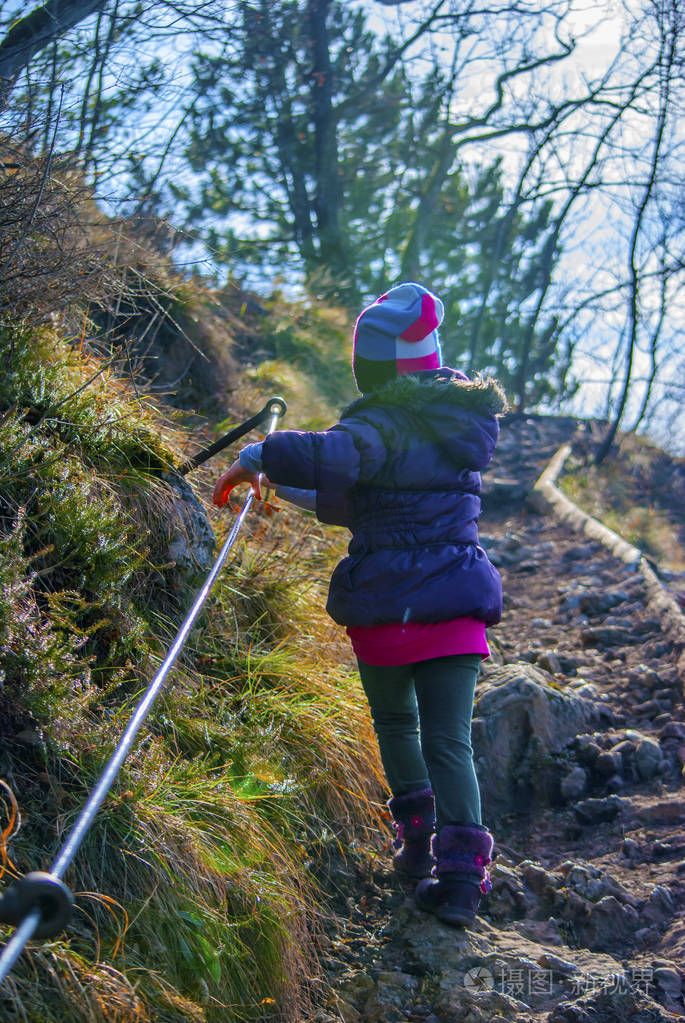 小女孩在阳光明媚的冬天早晨在上坡路上徒步旅行持有钢线