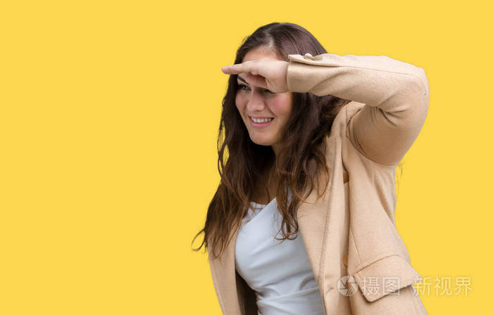 穿着冬天的外套,在孤立的背景下,非常高兴和微笑,用手捂住头看着远方