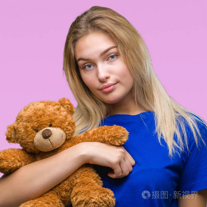 年轻的白种人女人抱着可爱的泰迪熊在孤立的背景下充满自信的表情聪明