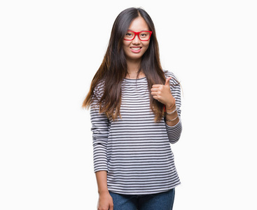 年轻的亚洲女人戴着眼镜，在孤立的背景上，用手做快乐的拇指向上的手势。 赞许的表情看着相机，显示出成功。