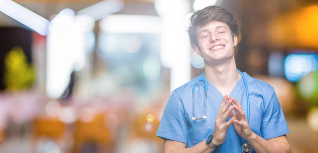 年轻的医生穿着医疗制服，双手分开，手指交叉微笑，轻松愉快。 成功和乐观