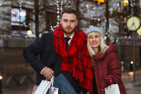这对幸福的年轻夫妇拿着购物袋站在街上的画像