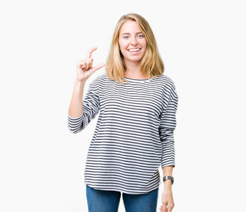 美丽的年轻女子穿着条纹毛衣，在孤立的背景上微笑和自信的手势，用手做大小标志，同时看和相机。 测量概念。