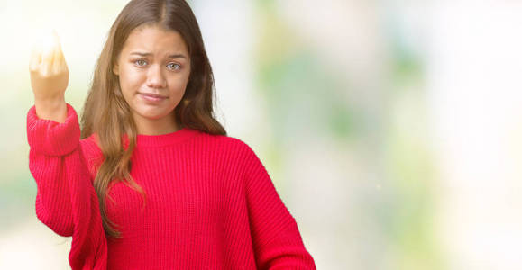 年轻美丽的黑发女子，穿着红色冬季毛衣，背景与世隔绝。用手和手指做意大利手势，自信的表情