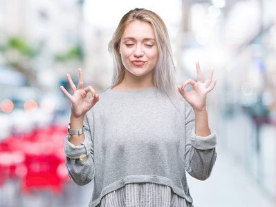 年轻的金发女子在孤立的背景下放松和微笑，闭着眼睛做冥想手势与手指。 瑜伽概念。