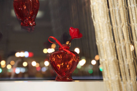 城市灯光背景下窗台上红色心形的小花瓶