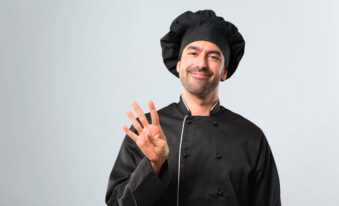 穿着黑色制服的厨师高兴地数着四个手指在灰色背景下