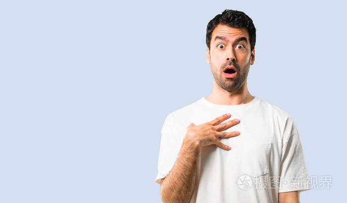 穿着白色衬衫的年轻人惊讶和震惊同时向右看孤立蓝色背景下的面部表情
