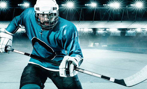 冰球运动员在体育场的头盔和手套上拿着棍子.行动射击.运动理念照片