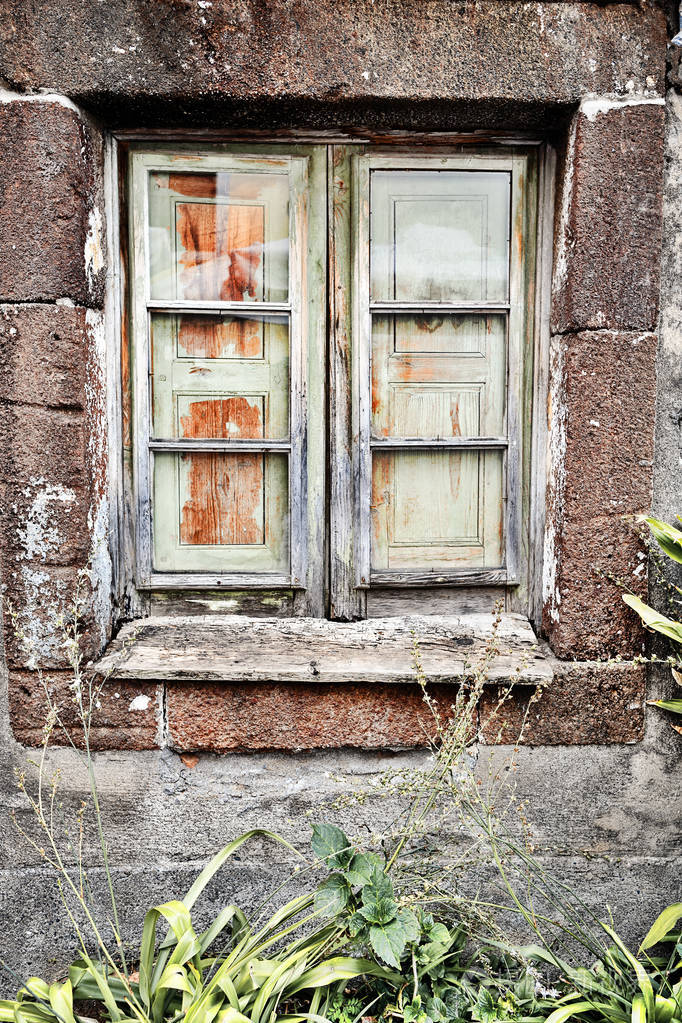 葡萄牙马德拉一座古老的石屋里的一个破旧的木窗