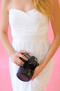 特写镜头女摄影师与相机在粉红色的单声道背景