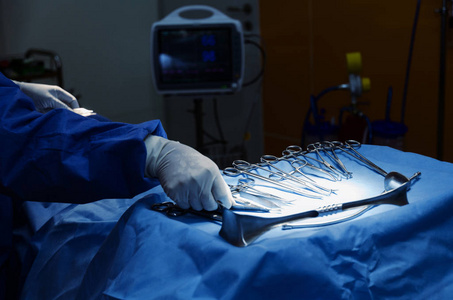 外科医生手拿剪刀钳和手术器械放在桌子上，与同事一起在医院急诊手术室工作，医学概念
