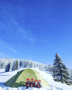 帐篷冬天的山。帐篷矗立在雪地里的山上。 雪鞋在帐篷旁边。