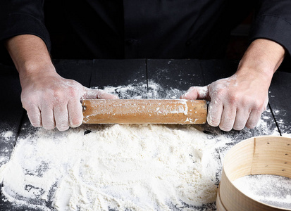 s hands, white wheat flour is poured on the table