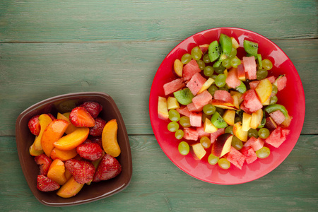 木制背景上的水果沙拉。 一盘水果素食沙拉