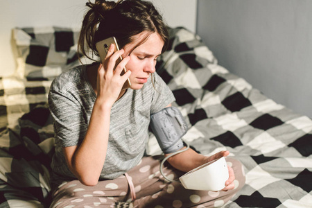 美丽的年轻女子使用自动调色仪检查家里的压力在卧室的床上.