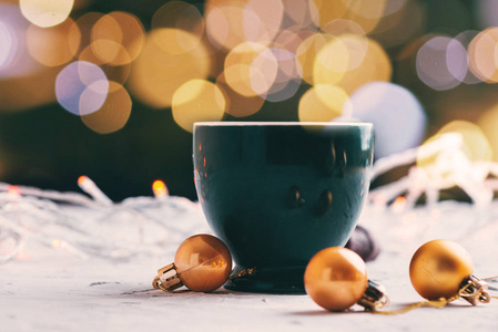 带有灯光的咖啡杯，金色的球，背景模糊的圣诞节
