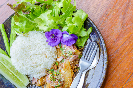 鱼辣沙拉，豌豆花，生菜，黄瓜在盘子里。食物在木桌上。