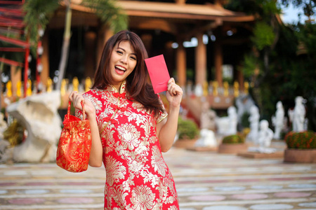 一个美丽的亚洲女人的肖像持有幸运的钱和红色口袋中国新年概念。