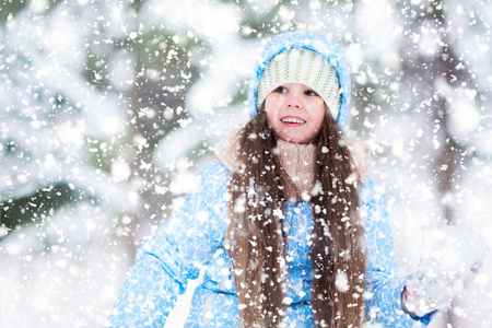 一个快乐的女孩正在雪地森林里玩雪球。