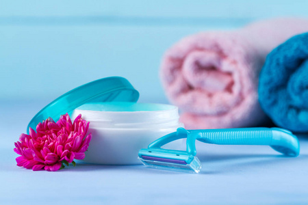 s shaving razor, towels and a pink flower on blue background. De