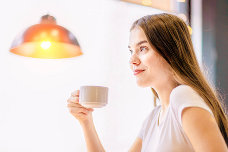 一个女孩在喝咖啡，体贴地微笑着。