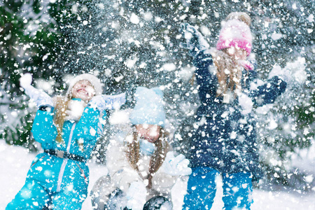 三个女孩兴高采烈地在冬季公园里吐雪玩耍。