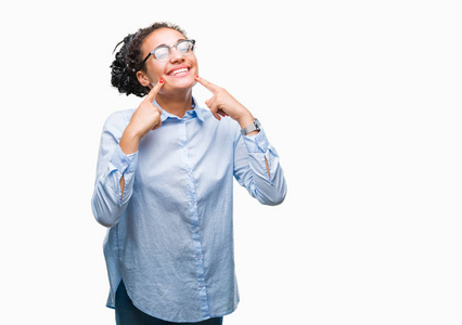 年轻的辫子非洲裔美国商业女孩戴着眼镜，在孤立的背景上微笑，自信地展示和指着手指，牙齿和嘴。 健康概念。
