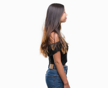 年轻的亚洲女人在孤立的背景下,看着侧面放松的轮廓姿势,自然的脸