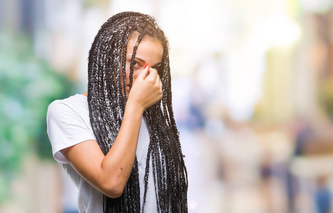 年轻的辫子非裔美国女孩在孤立的背景下疲惫地鼻子和眼睛，感到疲劳和头痛。 压力和挫折的概念。