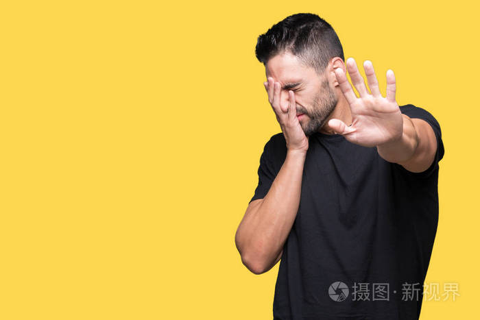 年轻的帅哥在孤立的背景上用手遮住眼睛用悲伤和恐惧的表情做停止的