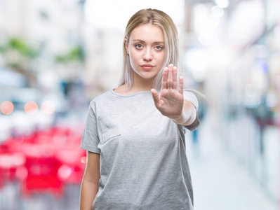 年轻的金发女人在孤立的背景下做停止用手掌唱歌。 警告表情，脸上有负面和严肃的手势。