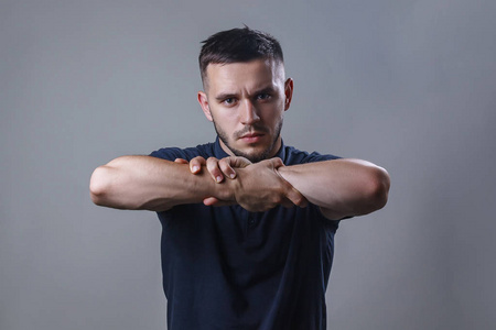 特写一位年轻严肃男子的肖像,他自己抓住手臂.