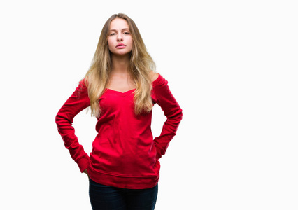 年轻漂亮的金发女人穿着红色毛衣，在孤立的背景上，脸上有严肃的表情。 简单自然地看着相机。